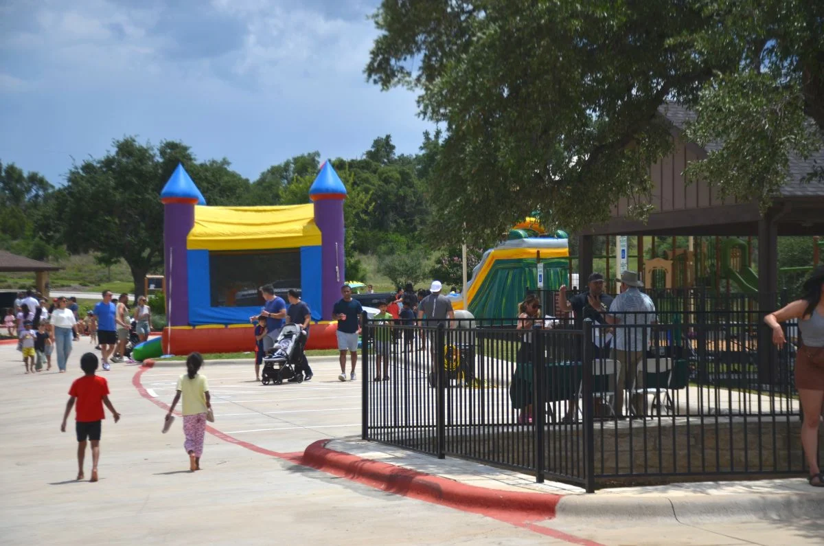 A Provence community event featuring families and a bounce house in the background.