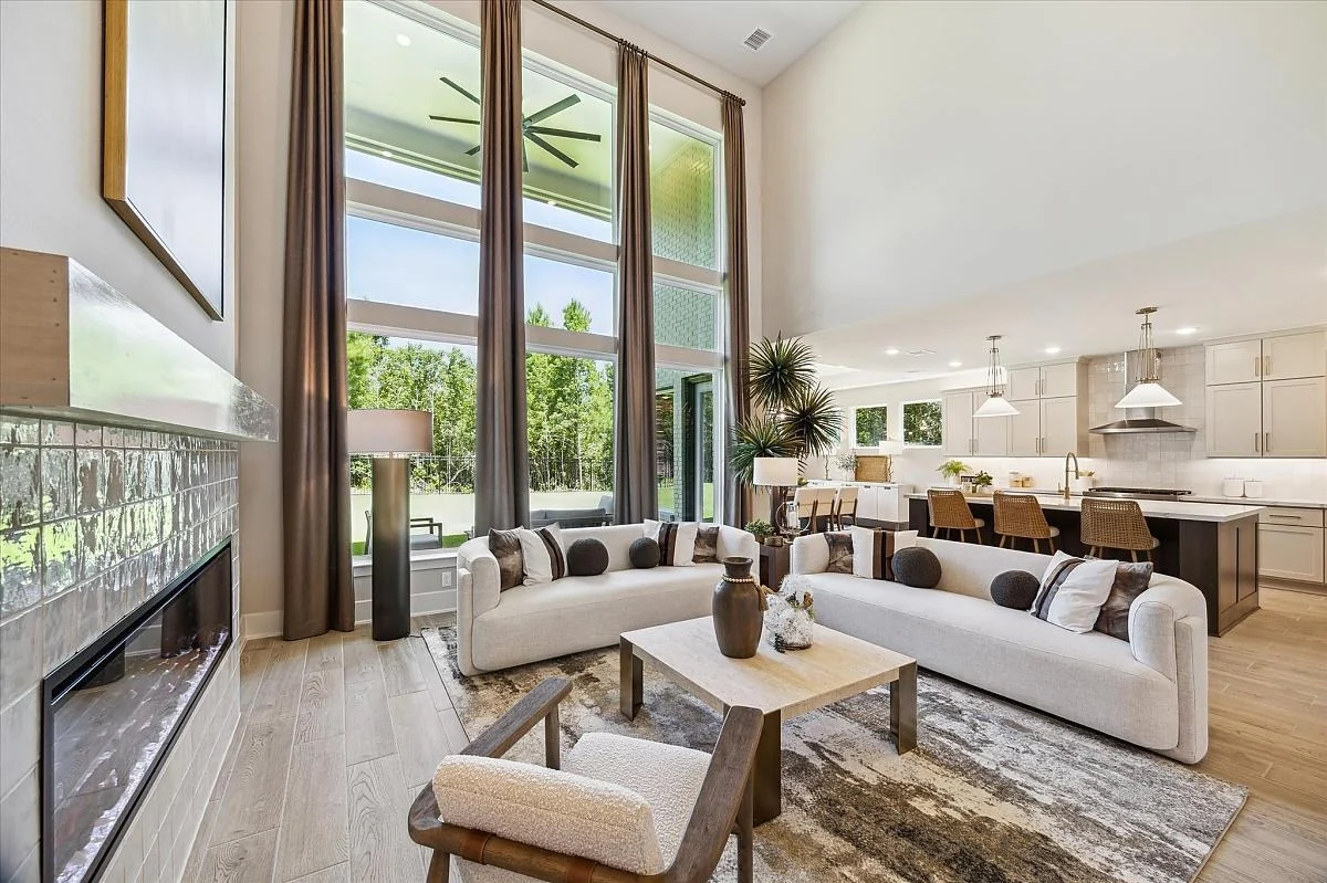 Interior living room view of a Provence home with floor to ceiling windows and fireplace.