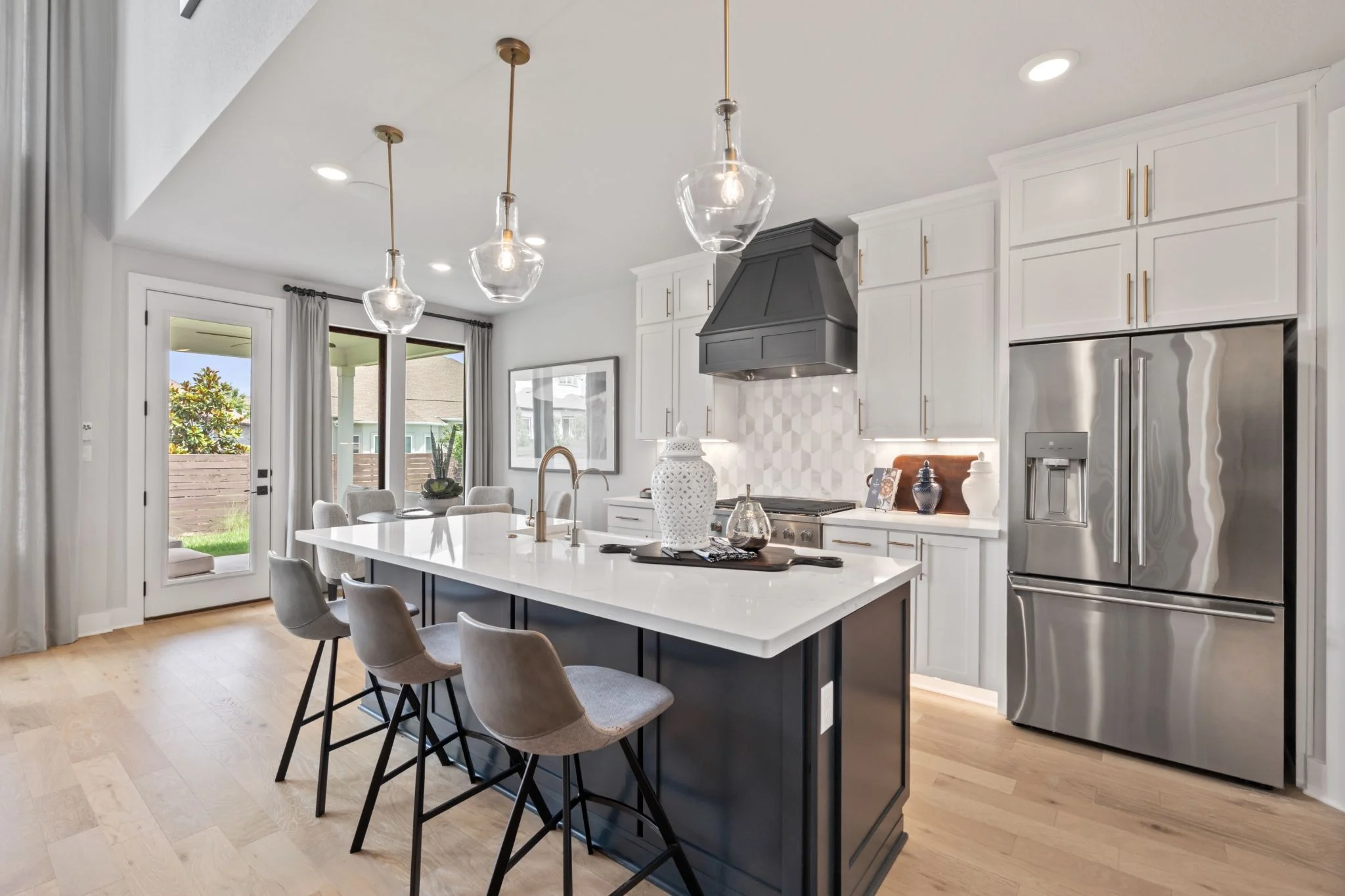 Interior kitchen view of a Provence home featuring while cabinets and stainless steel appliances.